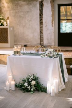 a table with candles and flowers on it in the middle of a room filled with chairs