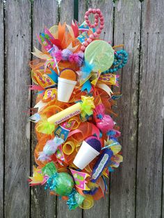 a wreath made out of plastic cups and streamers is hanging on a wooden fence