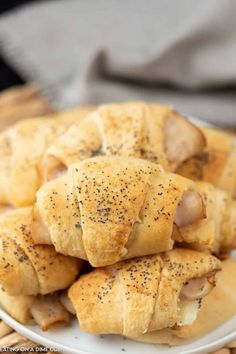 a white plate topped with pigs in a blanket next to breadsticks on top of a wicker table