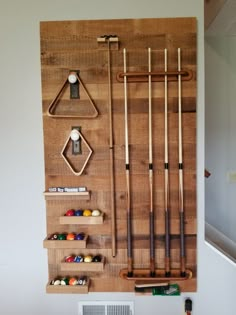 a wooden board with pool cues, cues and balls hanging on it's wall