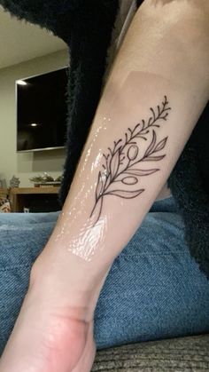 a person with a tattoo on their arm that has a branch and leaves on it