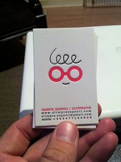 a person holding up a business card with glasses on it