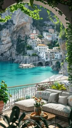 an outdoor patio with a view of the ocean and houses on the cliff above it