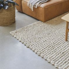 a living room with a brown couch and white rugs on the floor next to a coffee table