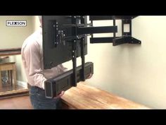 a man is standing in front of a wall mounted flat screen tv on a wooden table