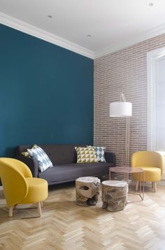 a living room with blue walls and yellow chairs on the floor next to a coffee table