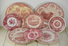 an assortment of red and white plates on a wooden floor with one plate in the middle