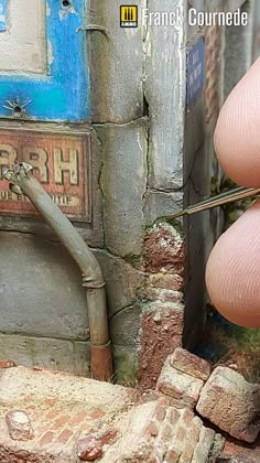 a person is holding a pair of scissors in front of a brick wall with graffiti on it