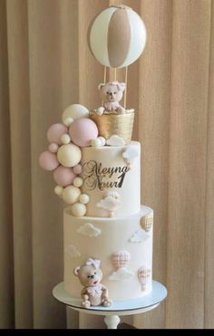 a three tiered cake decorated with balloons and teddy bears