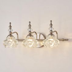 three light bathroom fixture with clear glass globes on the sides and an antique brass finish