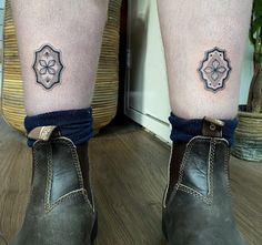 two tattoos on the legs of a person with brown boots and blue socks, one has an umbrella