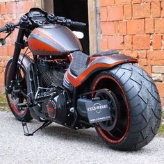 an orange and black motorcycle parked in front of a brick building