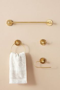 a towel hanging on the wall next to two gold hooks and a towel rack with three towels