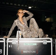 a woman sitting on top of a metal box