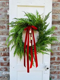 a wreath with red ribbon hanging on a door