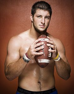 a shirtless man holding a football in his hands