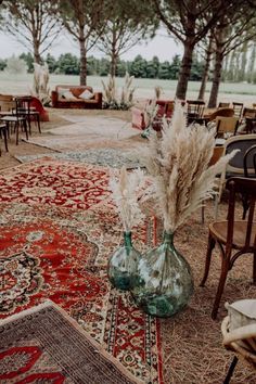 an area with chairs, tables and rugs is shown in front of the trees