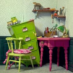 a green dresser sitting next to a pink table with a chair on top of it