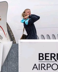 a woman standing on the wing of an airplane with her hand in her pocket as she looks off into the distance