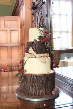 a three tiered cake is decorated with red berries and greenery