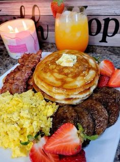 the breakfast plate has pancakes, sausages, strawberries and other foods on it