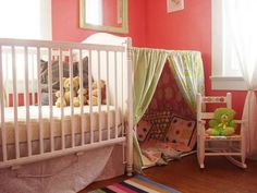 a baby crib in the corner of a room with pink walls and green curtains