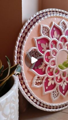 a decorative plate sitting on top of a table next to a potted succulent