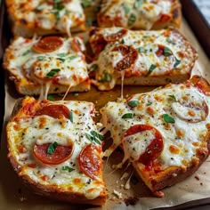 several slices of pizza on a tray with cheese and tomato toppings are being cut into small pieces