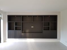 an empty room with black bookcases and white walls