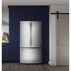 a stainless steel refrigerator in a kitchen with blue cabinets