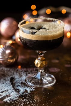 a glass filled with liquid sitting on top of a table next to christmas ornaments and baubles