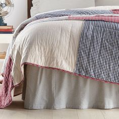 a bed with a plaid bedspread on top of it next to a fan