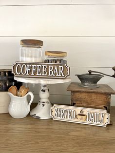 coffee bar sign displayed on wooden table next to white pitcher and old fashioned grinder