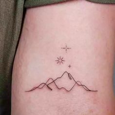 a small tattoo on the side of a woman's stomach with mountains in the background