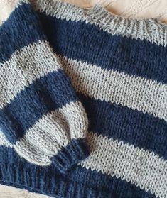 a blue and white striped sweater laying on top of a bed