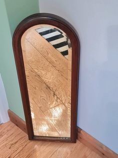 a mirror sitting on top of a hard wood floor next to a blue painted wall