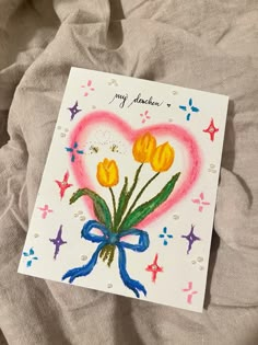 a handmade card with yellow tulips in a heart - shaped frame on a bed