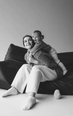 a woman sitting on top of a bean bag chair holding a baby in her arms