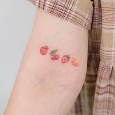 a woman's arm with fruit tattoos on her left side, including strawberries and oranges