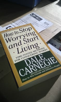 the book how to stop worrying and start living by dale carrenge is sitting on a table