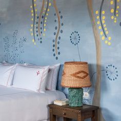 a bedroom decorated in blue and yellow with flowers on the wall behind the headboard