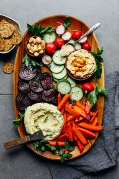 a platter with carrots, radishes, hummus and crackers