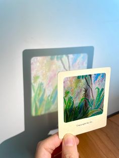 a person holding up a card with an image of a tree and flowers on it