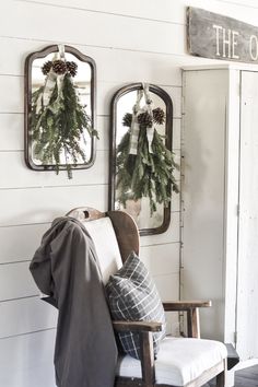 two mirrors hanging on the wall with christmas wreaths