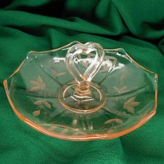 a glass plate with two hearts on it sitting on a green cloth covered tablecloth