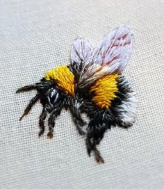 a yellow and black bee sitting on top of a white cloth