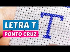 someone is stitching the letter t on a piece of fabric with blue and pink thread