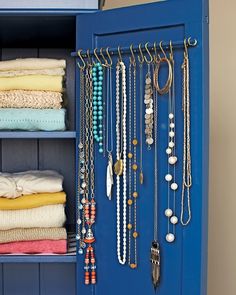 a blue cabinet filled with lots of necklaces and jewelry hanging from it's doors