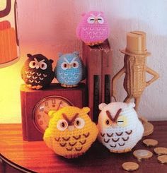 three crocheted owls sitting on top of a wooden table next to a clock