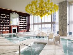 an indoor swimming pool with chairs and chandelier in the middle, surrounded by large windows